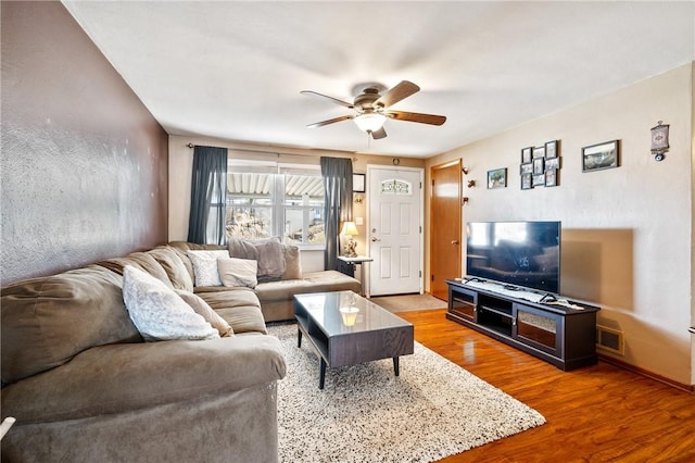 living area featuring a ceiling fan, visible vents, and wood finished floors