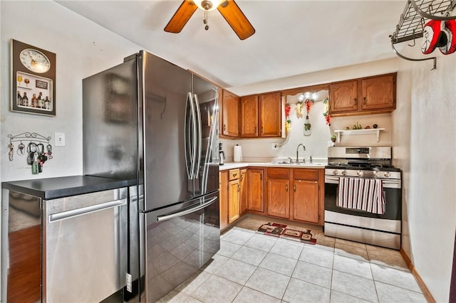 kitchen featuring ceiling fan, light tile patterned flooring, a sink, appliances with stainless steel finishes, and brown cabinets