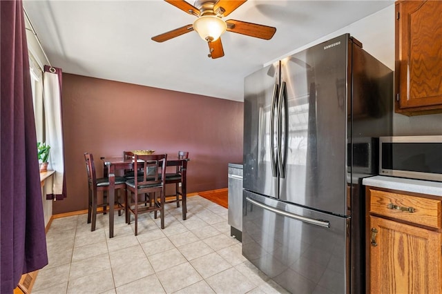 kitchen featuring light tile patterned floors, stainless steel appliances, a ceiling fan, baseboards, and light countertops