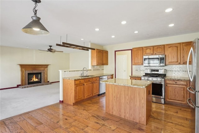 kitchen featuring appliances with stainless steel finishes, a kitchen island, a sink, and light stone countertops