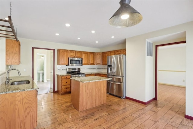 kitchen featuring stainless steel appliances, light stone counters, a sink, and decorative backsplash