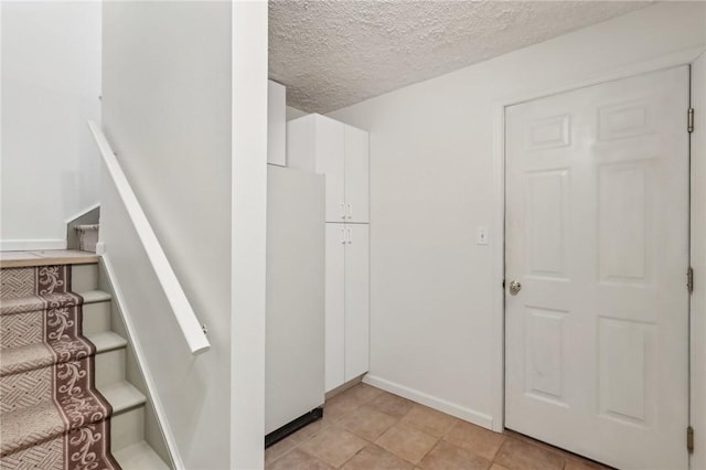 stairs with a textured ceiling and baseboards