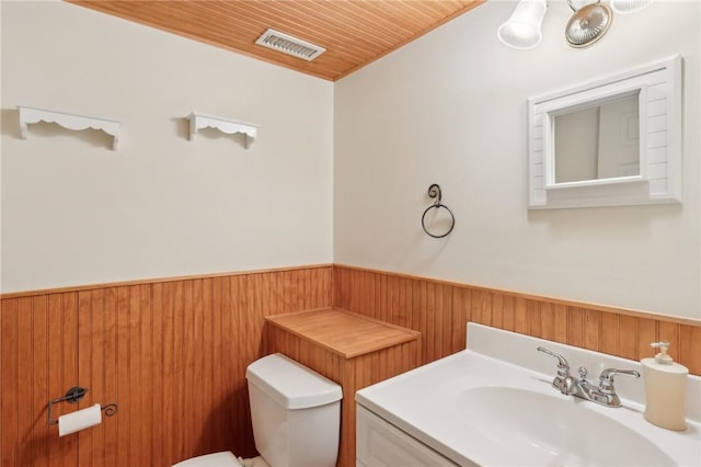 bathroom featuring visible vents, toilet, a wainscoted wall, wood ceiling, and wood walls