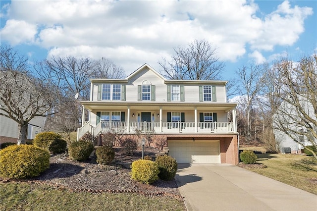 colonial home with a porch, concrete driveway, brick siding, and a garage