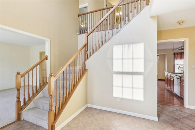 staircase with tile patterned floors, a towering ceiling, and baseboards