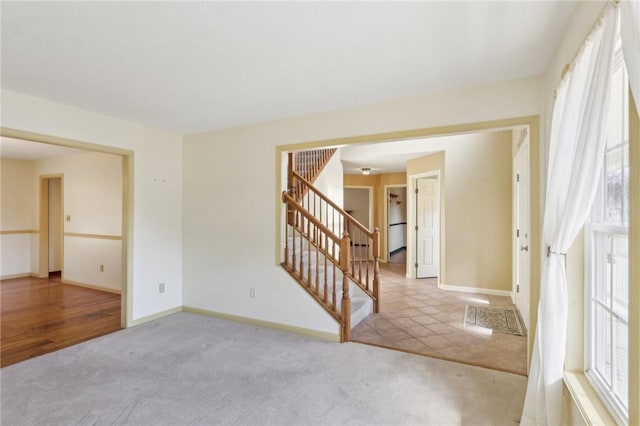 empty room featuring carpet floors, stairway, and baseboards