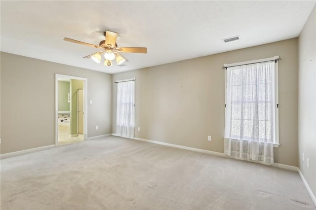 carpeted spare room with baseboards, visible vents, and ceiling fan