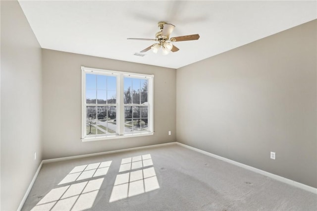 carpeted spare room with a ceiling fan, visible vents, and baseboards