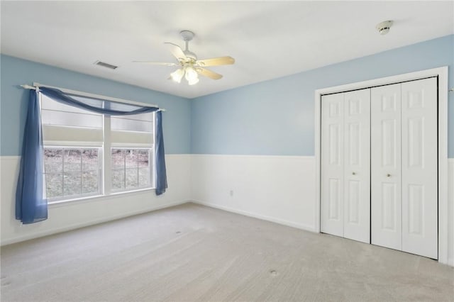 unfurnished bedroom featuring a closet, visible vents, ceiling fan, and carpet flooring