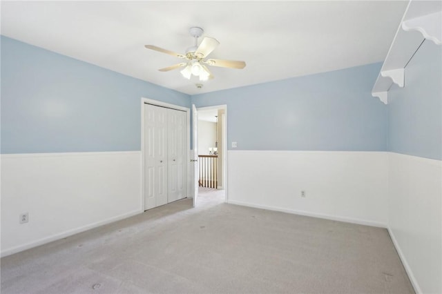 carpeted empty room featuring a ceiling fan and baseboards