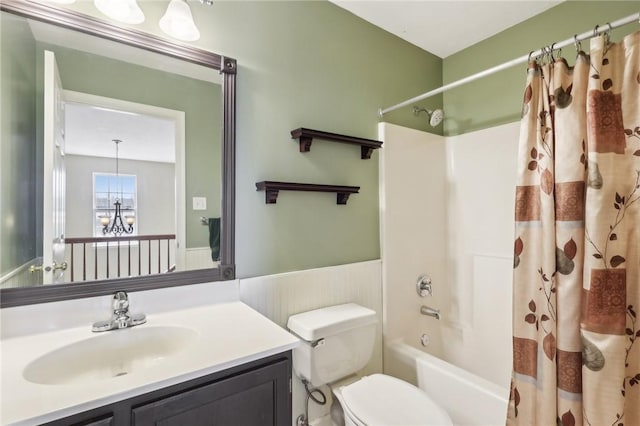 bathroom featuring a chandelier, toilet, a wainscoted wall, shower / tub combo, and vanity