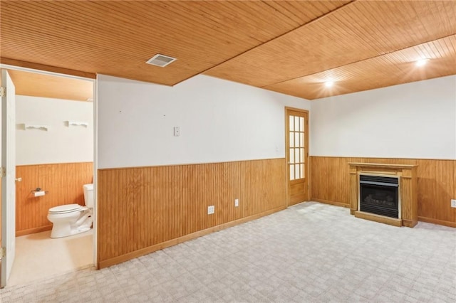 interior space featuring visible vents, wainscoting, wood ceiling, wood walls, and a fireplace