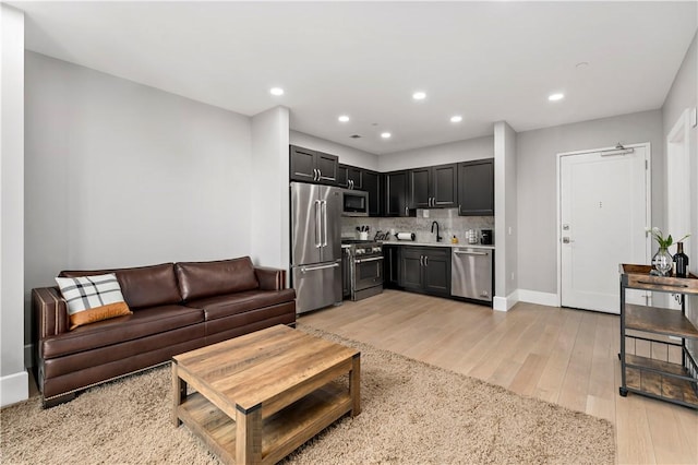 living room with recessed lighting, baseboards, and light wood finished floors