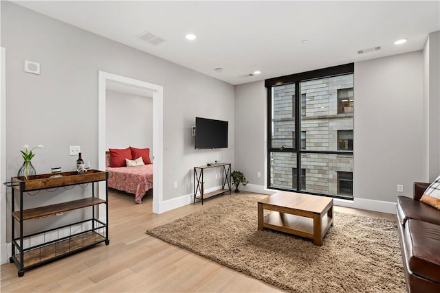 living area with recessed lighting, wood finished floors, visible vents, baseboards, and a glass covered fireplace