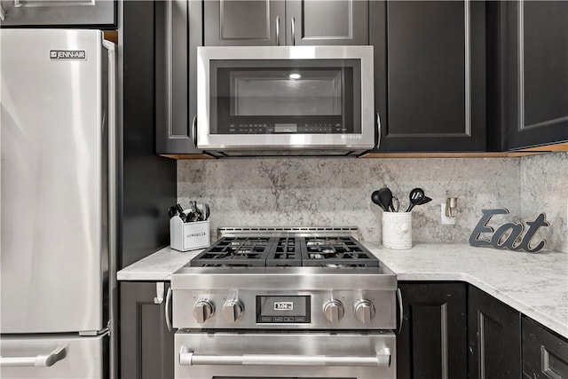 kitchen with stainless steel appliances, light countertops, dark cabinetry, and backsplash