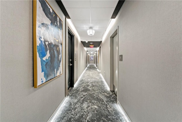 corridor with concrete flooring and attic access