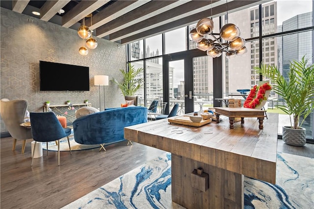 living area featuring wallpapered walls, wood finished floors, an inviting chandelier, expansive windows, and beam ceiling