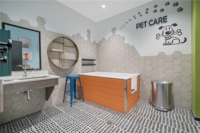 full bathroom with a garden tub, a sink, tile walls, and tile patterned floors