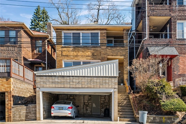 view of front of property featuring a garage, brick siding, and stairs