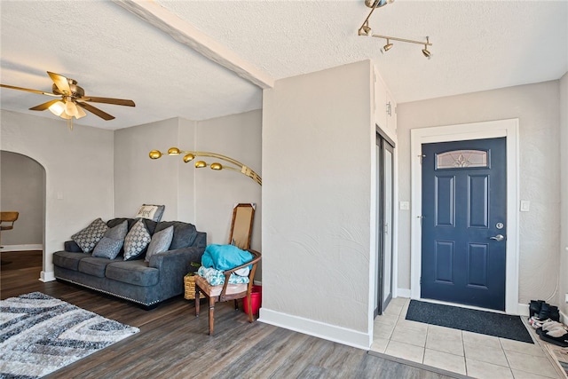 interior space featuring arched walkways, a textured ceiling, baseboards, and wood finished floors