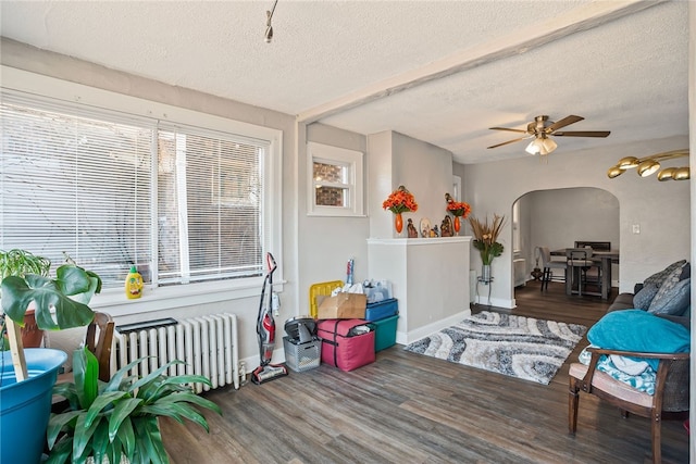 interior space with a ceiling fan, arched walkways, and radiator