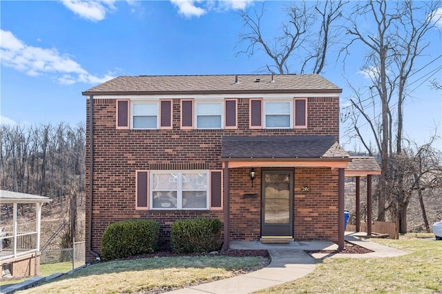 view of front of house with a front yard, brick siding, fence, and roof with shingles