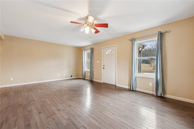 interior space featuring baseboards, visible vents, a ceiling fan, and wood finished floors