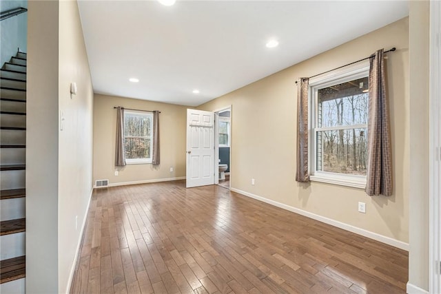 unfurnished room with baseboards, visible vents, wood finished floors, stairs, and recessed lighting