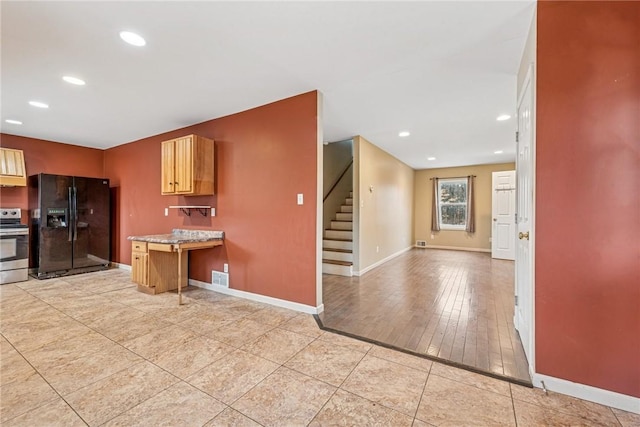 kitchen with baseboards, a peninsula, black fridge, and stainless steel electric stove