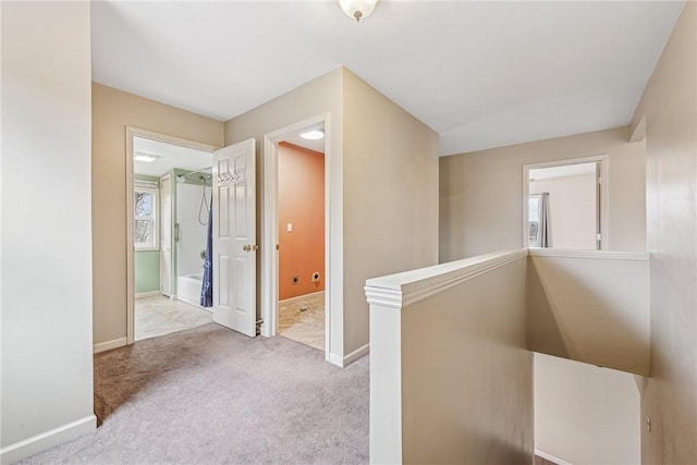 corridor featuring baseboards, carpet flooring, and an upstairs landing