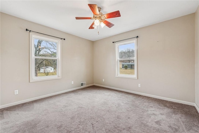 empty room featuring a ceiling fan, carpet flooring, visible vents, and baseboards