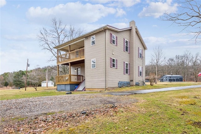 view of side of home featuring a lawn, a chimney, and a balcony