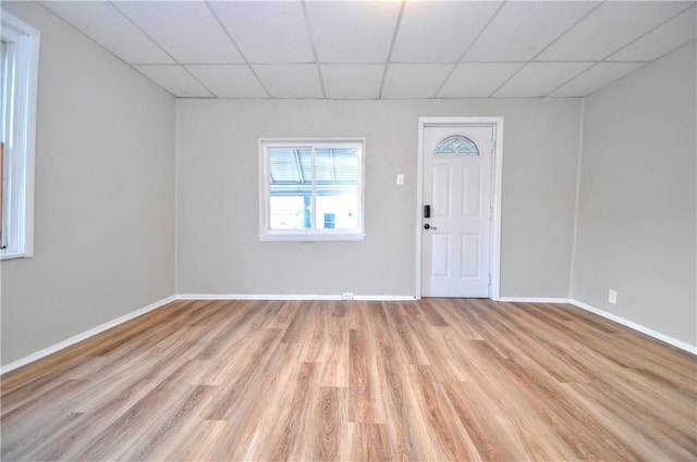 entryway with light wood-type flooring, a paneled ceiling, and baseboards