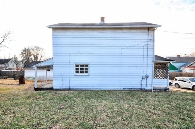 rear view of property featuring fence and a lawn