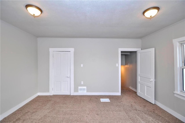 unfurnished bedroom featuring carpet floors, ornamental molding, visible vents, and baseboards