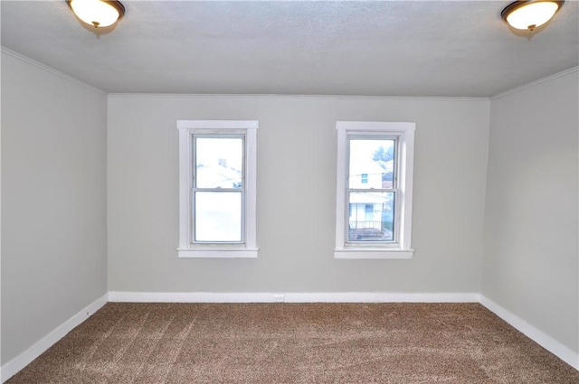 carpeted empty room with baseboards, ornamental molding, and a healthy amount of sunlight