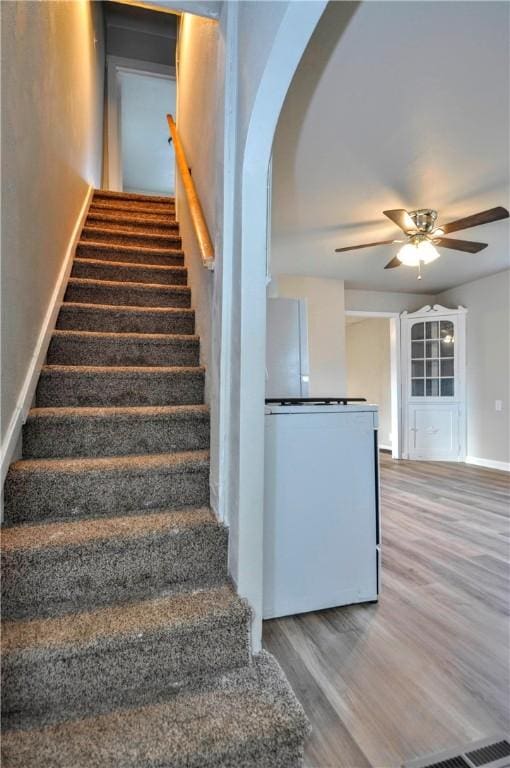 stairway with baseboards, a ceiling fan, and wood finished floors