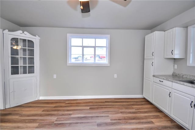 kitchen with a ceiling fan, white cabinetry, baseboards, and wood finished floors