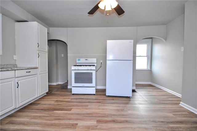 kitchen featuring arched walkways, light wood-style flooring, white cabinets, ceiling fan, and white appliances