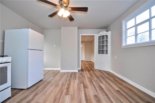 kitchen with white appliances, wood finished floors, a ceiling fan, and baseboards