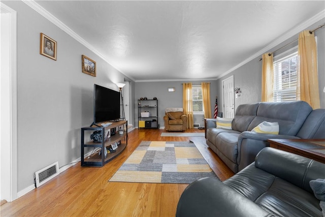 living room featuring visible vents, crown molding, baseboards, and wood finished floors