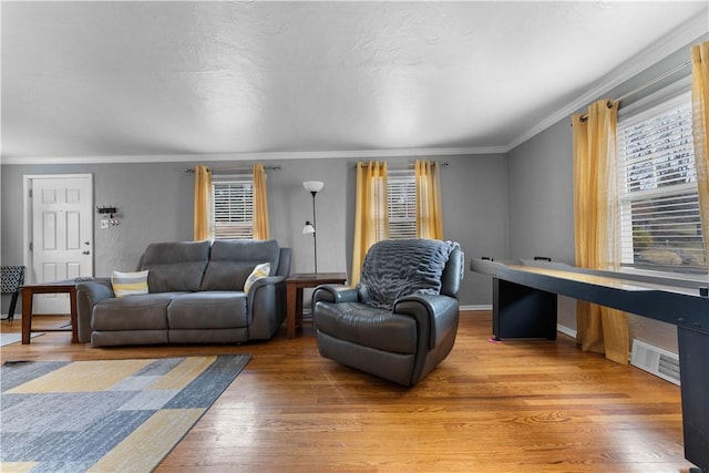 living area with visible vents, ornamental molding, a wealth of natural light, and light wood-style floors