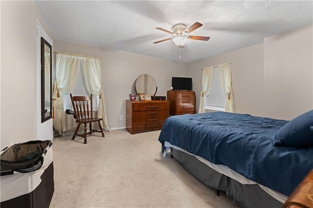 bedroom featuring a ceiling fan, light carpet, a textured ceiling, and baseboards