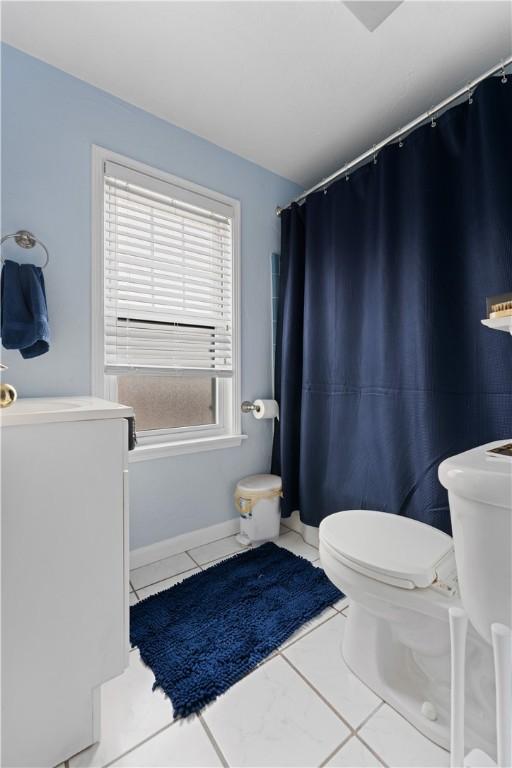 full bath with washer / dryer, tile patterned flooring, and toilet