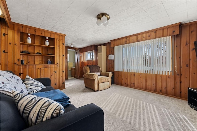 carpeted living area featuring built in shelves, wooden walls, and baseboards