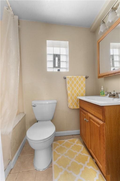 bathroom with a healthy amount of sunlight, vanity, toilet, and tile patterned floors