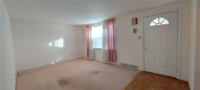 foyer entrance featuring carpet floors and visible vents