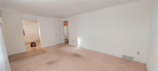 empty room featuring carpet floors, an inviting chandelier, and visible vents