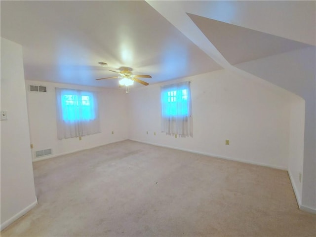 additional living space with visible vents, a wealth of natural light, and light colored carpet