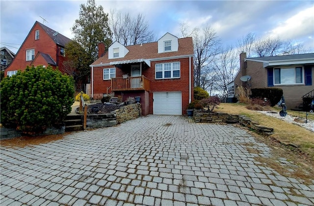 cape cod home featuring a garage, decorative driveway, and brick siding